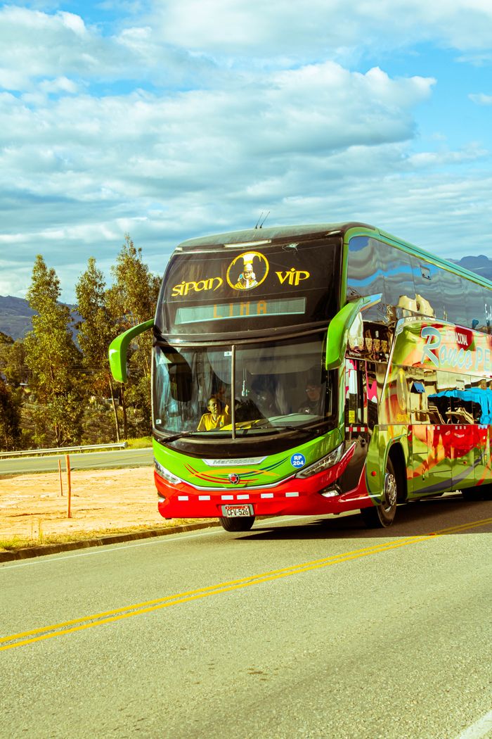 Colorful tour bus travels on a scenic highway with mountains and trees in view.